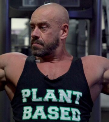 Vegan athlete Hench Herbivore wearing a vest top saying "Plant Based" while at the gym