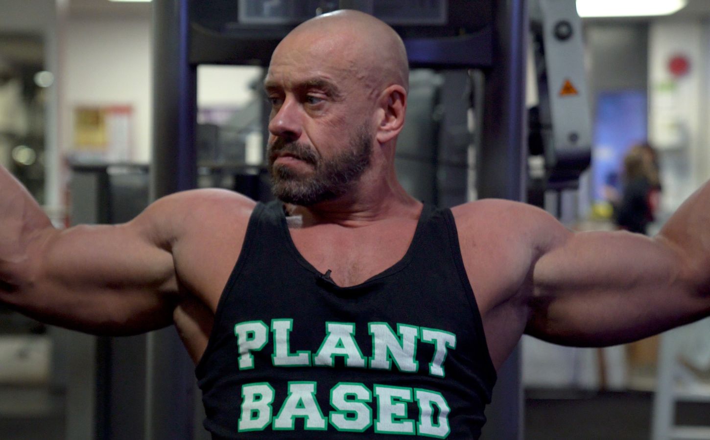 Vegan athlete Hench Herbivore wearing a vest top saying "Plant Based" while at the gym