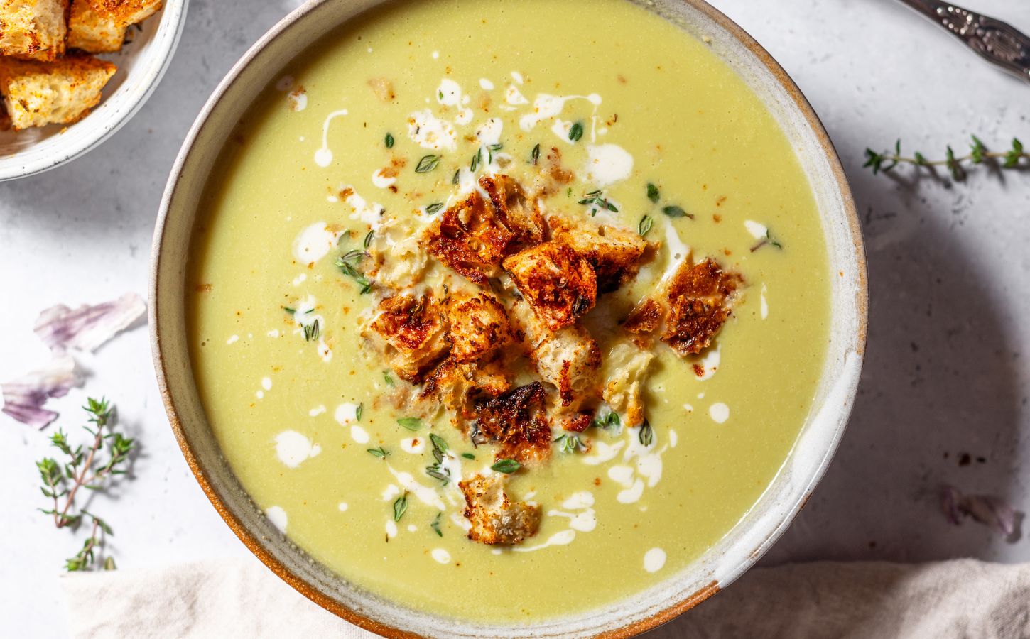 a bowl of vegan green asparagus soup made with celery, vegan cream, lemon zest, and thyme