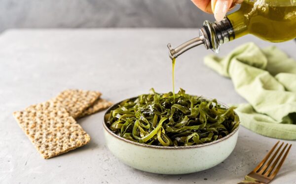 Photo shows a bowl of seaweed as someone drizzles olive oil over the top