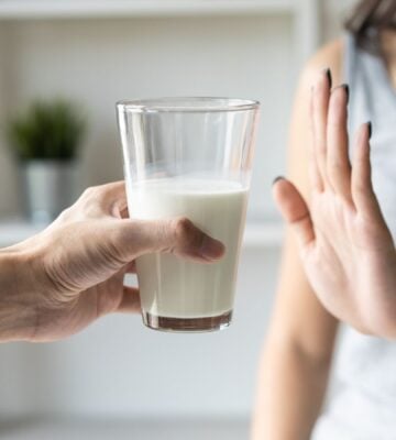 A person putting her hand up to reject a glass of dairy milk, which is linked to reduced risk of bowel cancer