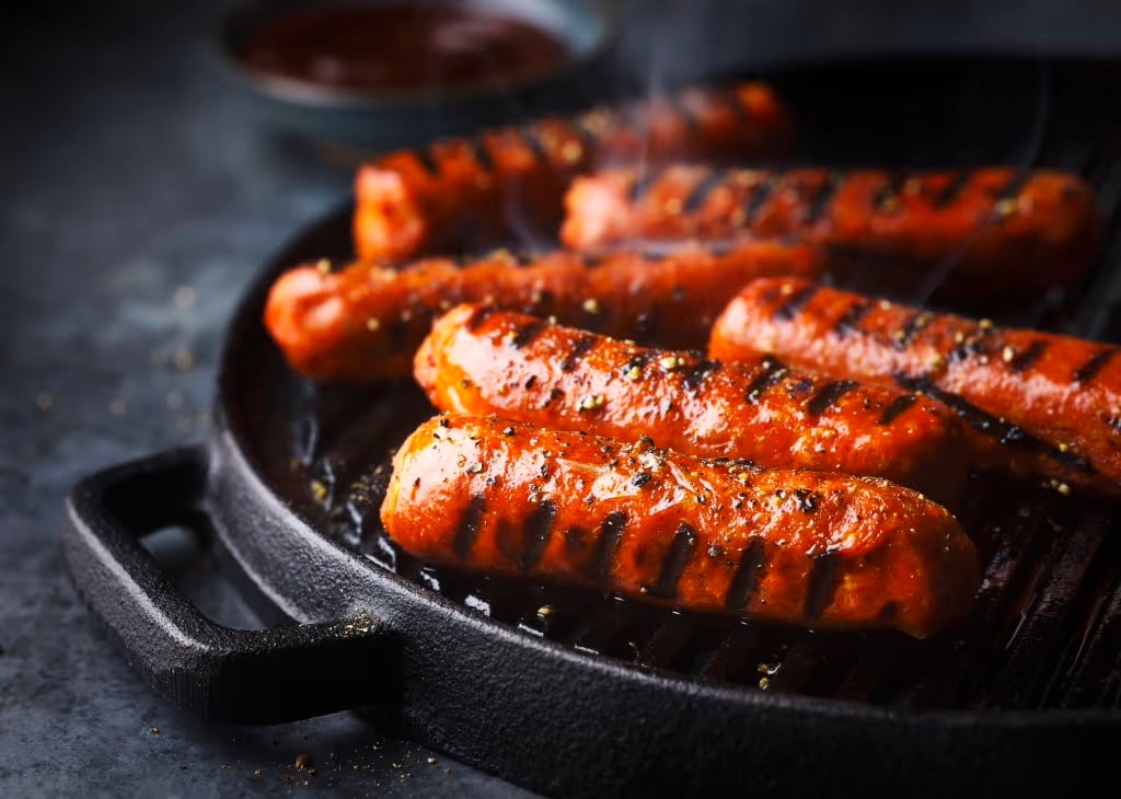 Plant Kitchen Smoky Veggie Sausages sizzling in a pan