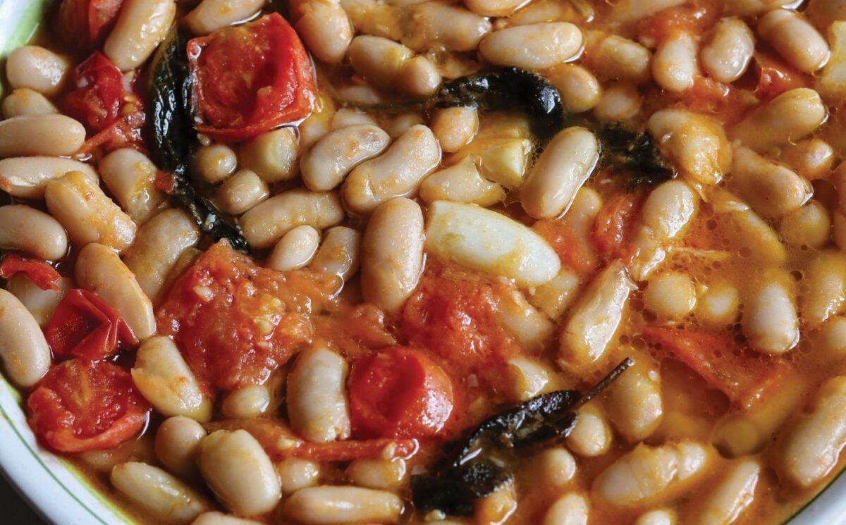 a close up of a vegan rustic tomato bean stew with sage and garlic for easy one-pot vegan recipes