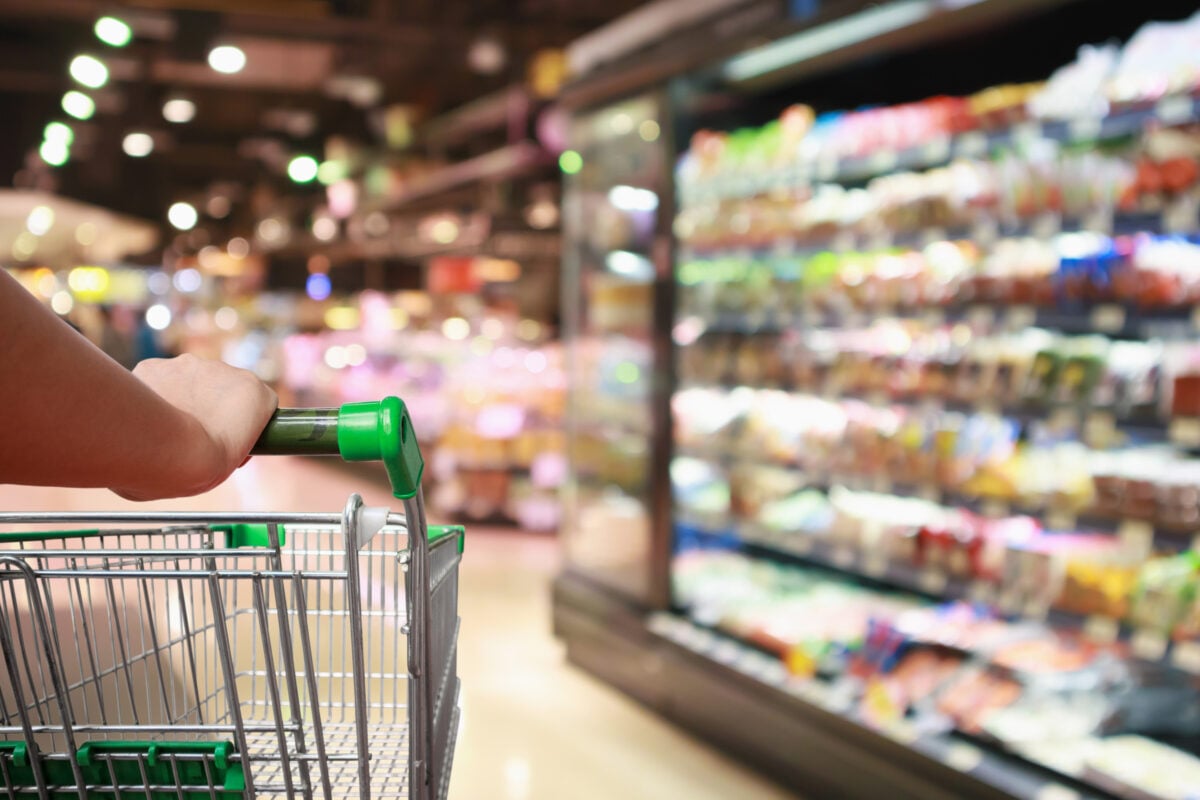 Photo shows someone's hand on a shopping trolley as they navigate a supermarket