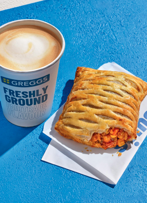 Photo shows the returning Greggs Spicy Vegetable Curry Bake alongside a cup of a coffee