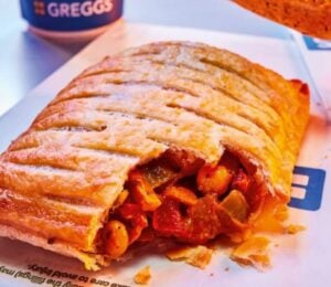 Photo shows the returning Greggs Spicy Vegetable Curry Bake alongside a cup of a coffee