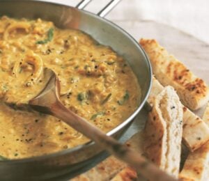 an example of high protein vegan recipes to make for Veganuary, a pan of coconut dhal with toasted naan fingers on the side