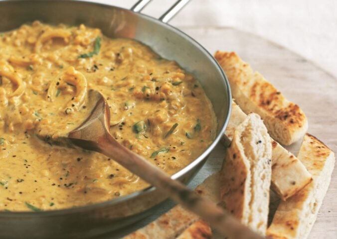 an example of high protein vegan recipes to make for Veganuary, a pan of coconut dhal with toasted naan fingers on the side