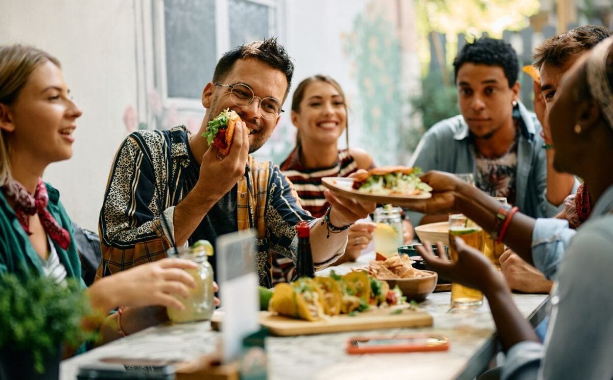 Photo shows a group of young people sat around a table at a Mexican restaurant eating tacos