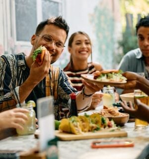 Photo shows a group of young people sat around a table at a Mexican restaurant eating tacos