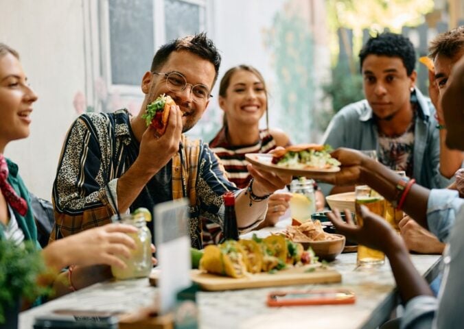 Photo shows a group of young people sat around a table at a Mexican restaurant eating tacos