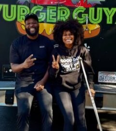 Photo shows Tabitha Brown and Vurger Guyz founder Na’eem Outler sat on the back of the Vurger Guyz food truck