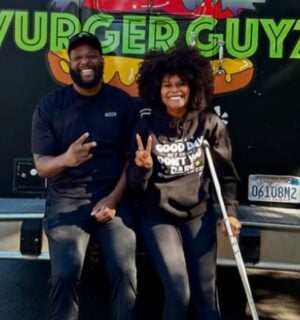 Photo shows Tabitha Brown and Vurger Guyz founder Na’eem Outler sat on the back of the Vurger Guyz food truck