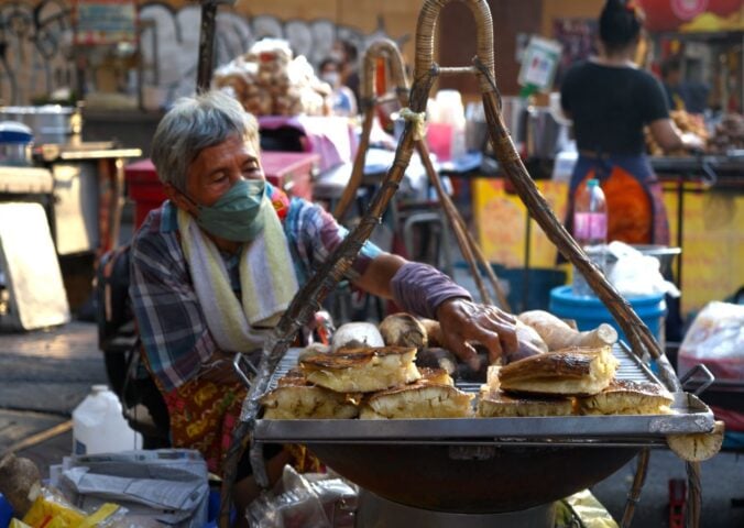 Photo shows a street food vendor cooking in Thailand