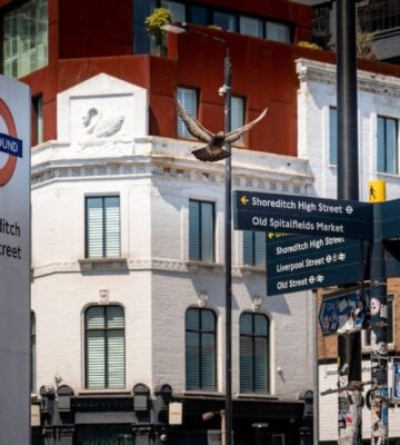An sign for the Shoreditch High Street Overground station next to some signs in the Hackney borough
