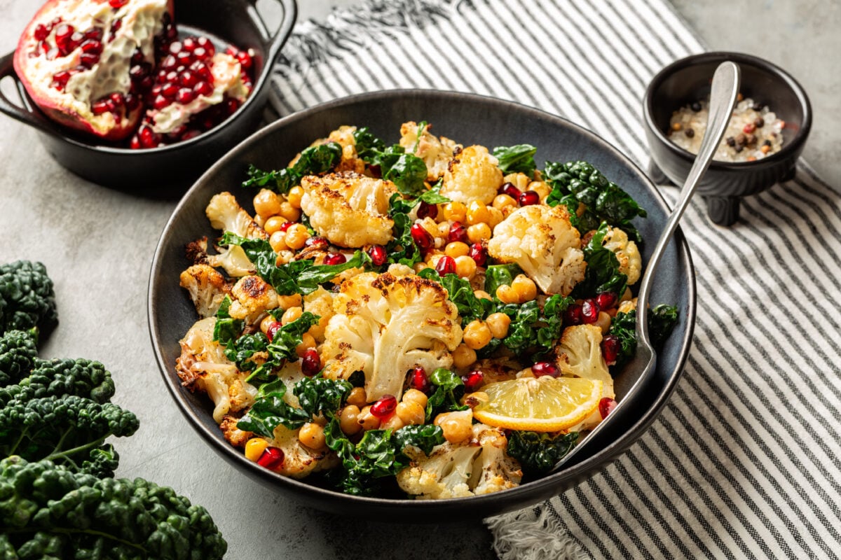 Photo shows a bowl full of plant-based food that is mostly roasted cauliflower and greens