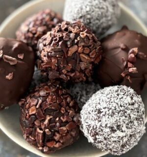 a picture of a bowl of vegan zero waste cake pops that are covered in chocolate, coconut, and cocoa nibs