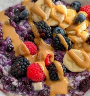 a bowl of 5-minute blueberry superfood oats with banana, nut butter, mixed berries, and chia seeds