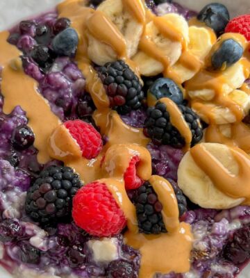 a bowl of 5-minute blueberry superfood oats with banana, nut butter, mixed berries, and chia seeds
