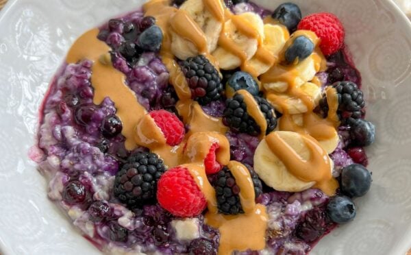 a bowl of 5-minute blueberry superfood oats with banana, nut butter, mixed berries, and chia seeds