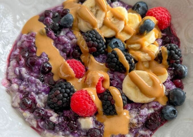 a bowl of 5-minute blueberry superfood oats with banana, nut butter, mixed berries, and chia seeds