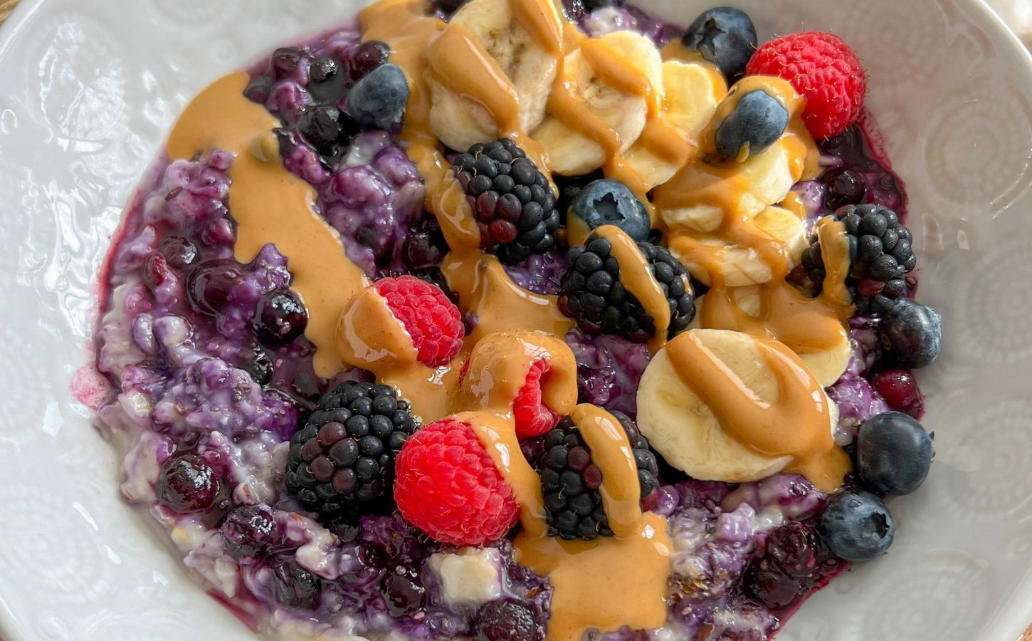 a bowl of 5-minute blueberry superfood oats with banana, nut butter, mixed berries, and chia seeds