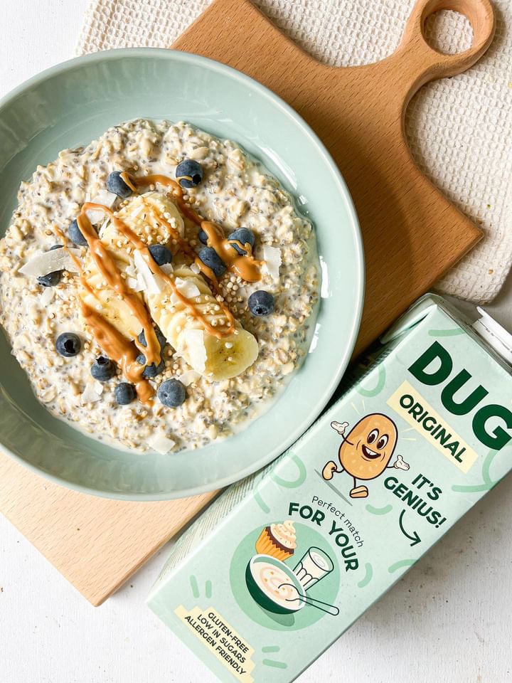 Photo shows a bowl of porridge and fruit next to a carton of DUG Original potato milk