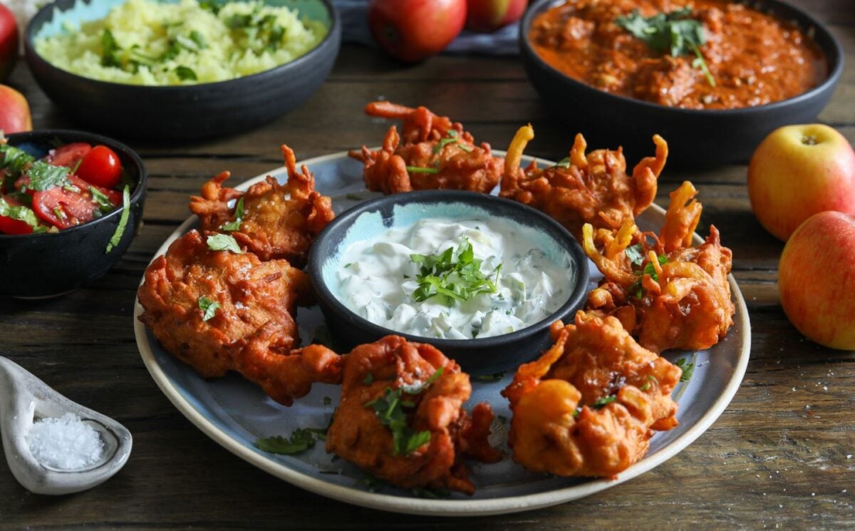 a plate of apple and onion bhajis with a dip