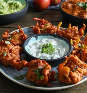 a plate of apple and onion bhajis with a dip