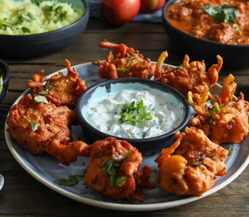 a plate of apple and onion bhajis with a dip