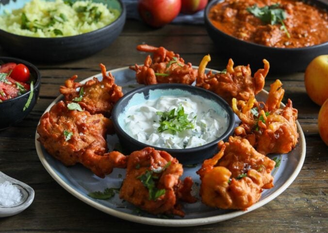 a plate of apple and onion bhajis with a dip