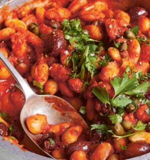 a bowl of butterbeans in tomato olive caper sauce with chili