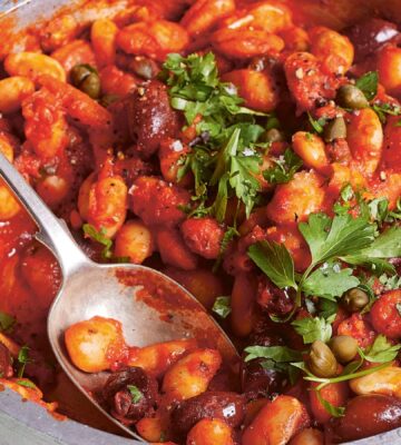 a bowl of butterbeans in tomato olive caper sauce with chili