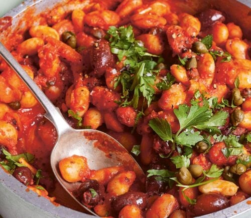 a bowl of butterbeans in tomato olive caper sauce with chili