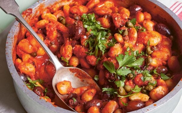 a bowl of butterbeans in tomato olive caper sauce with chili