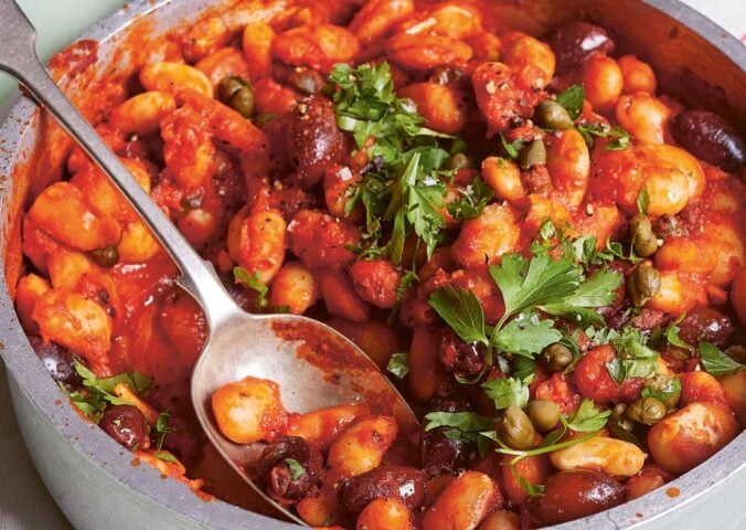 a bowl of butterbeans in tomato olive caper sauce with chili