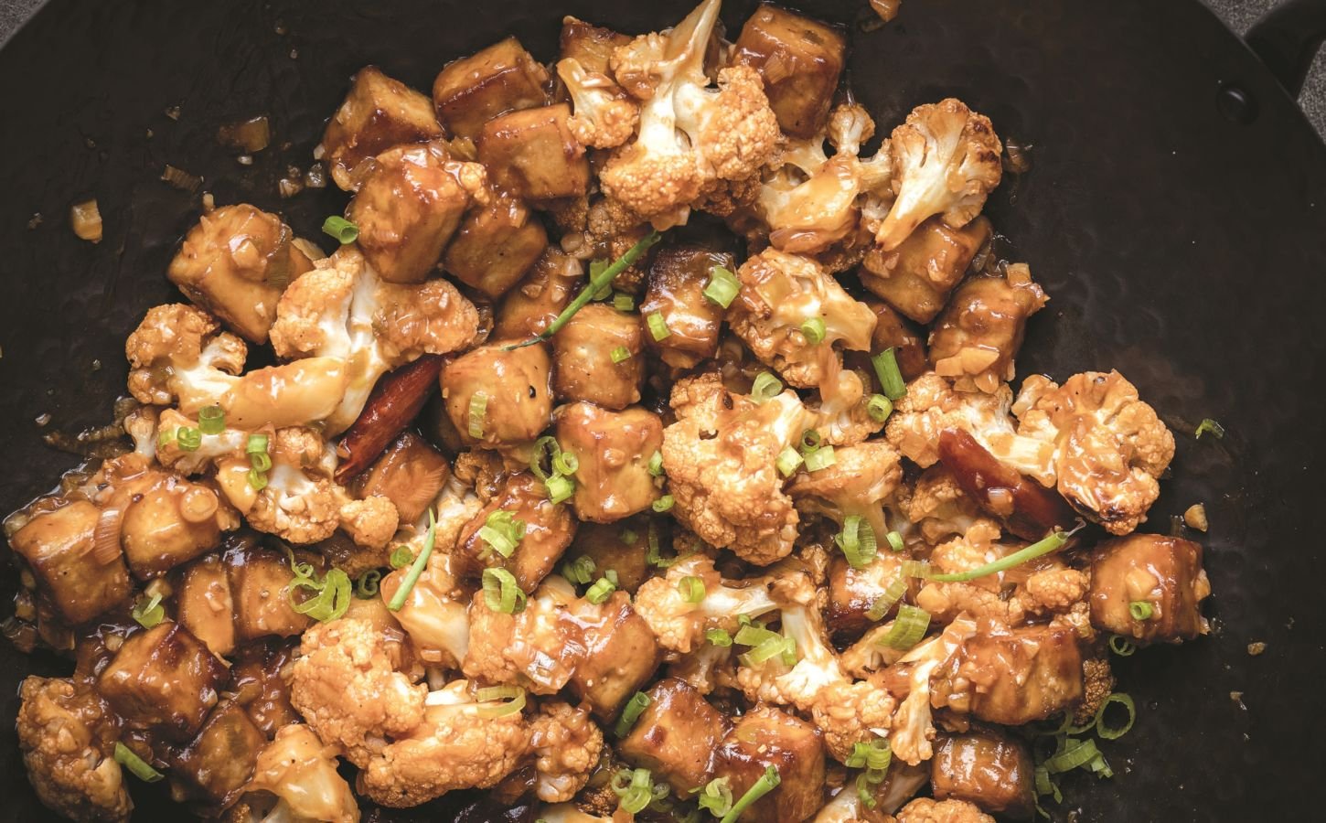 a wok full of vegan chili cauliflower and tofu