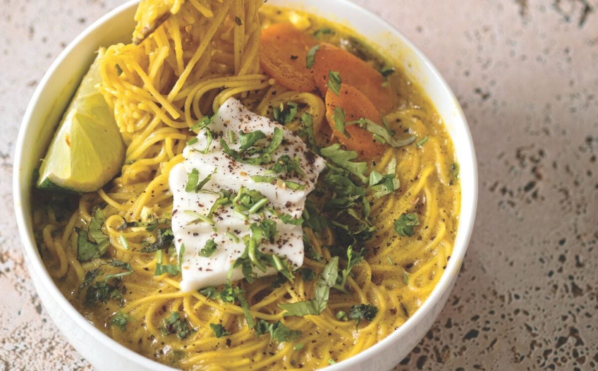 a bowl of vegan creamy coconut curry ramen with carrot, soft tofu, lime, and herbs