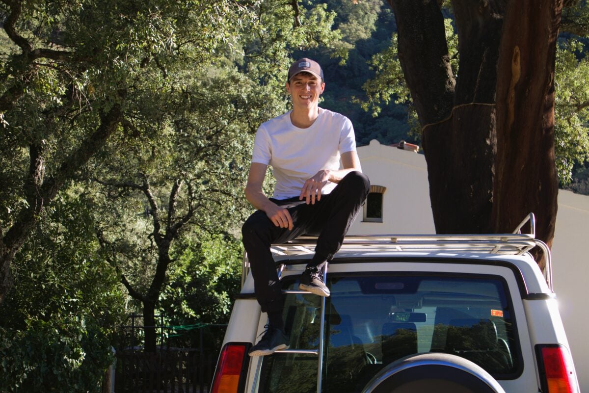 Vegan homesteader Luke Kelsall sitting on top of a car