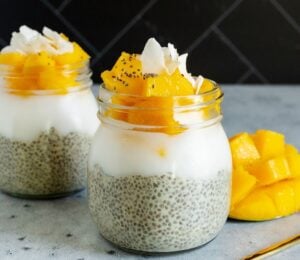 two jars of mango coconut chia seed pudding with sliced mango and coconut