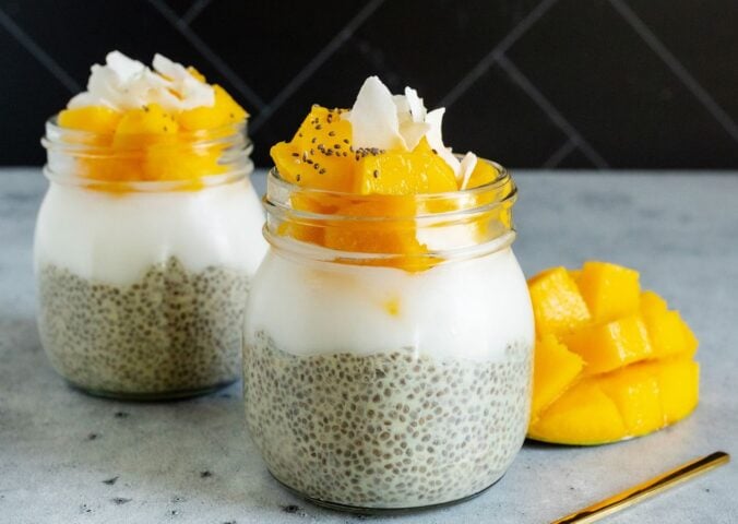 two jars of mango coconut chia seed pudding with sliced mango and coconut