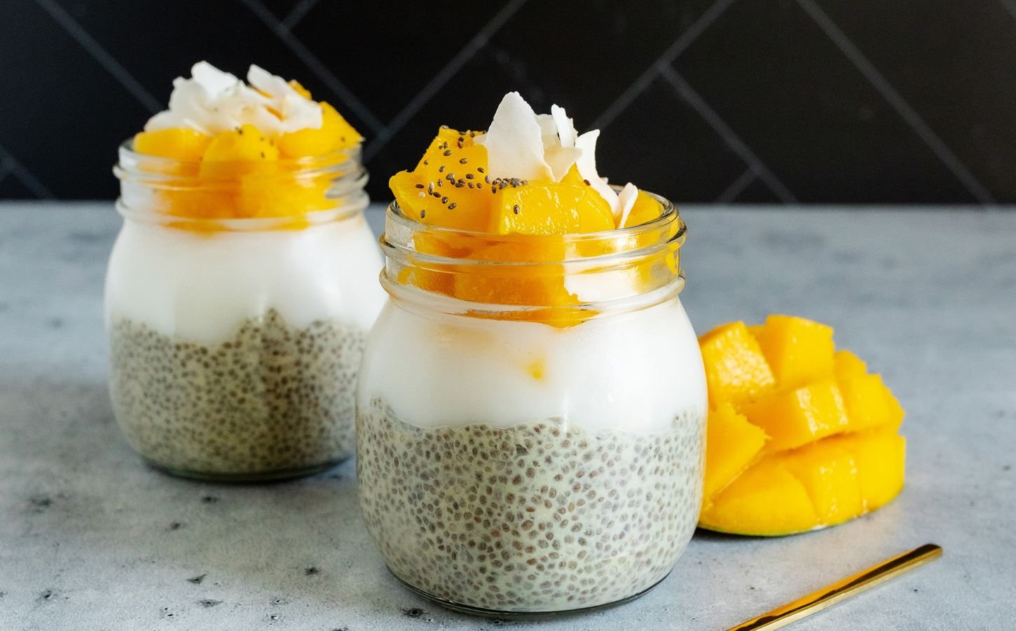 two jars of mango coconut chia seed pudding with sliced mango and coconut