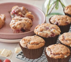 vegan raspberry and white chocolate muffins on a cooling rack in rows