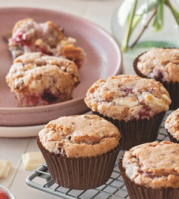 vegan raspberry and white chocolate muffins on a cooling rack in rows