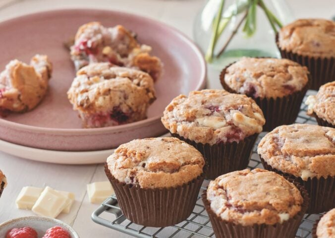 vegan raspberry and white chocolate muffins on a cooling rack in rows