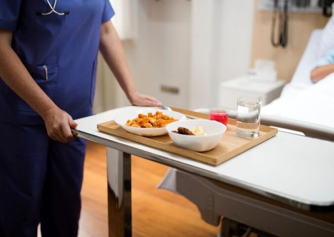 A nurse serving a patient plant-based hospital food