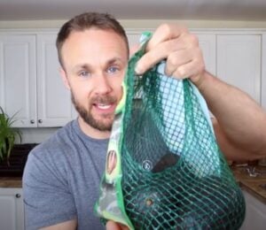 Plant-based nutritionist Derek Simnett holding up a pack of avocados for a video on vegan food hacks