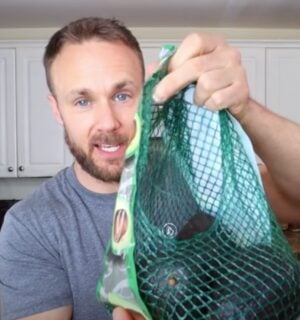 Plant-based nutritionist Derek Simnett holding up a pack of avocados for a video on vegan food hacks