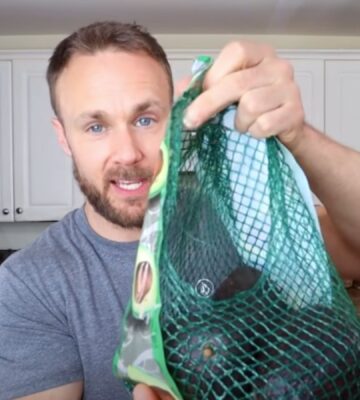 Plant-based nutritionist Derek Simnett holding up a pack of avocados for a video on vegan food hacks