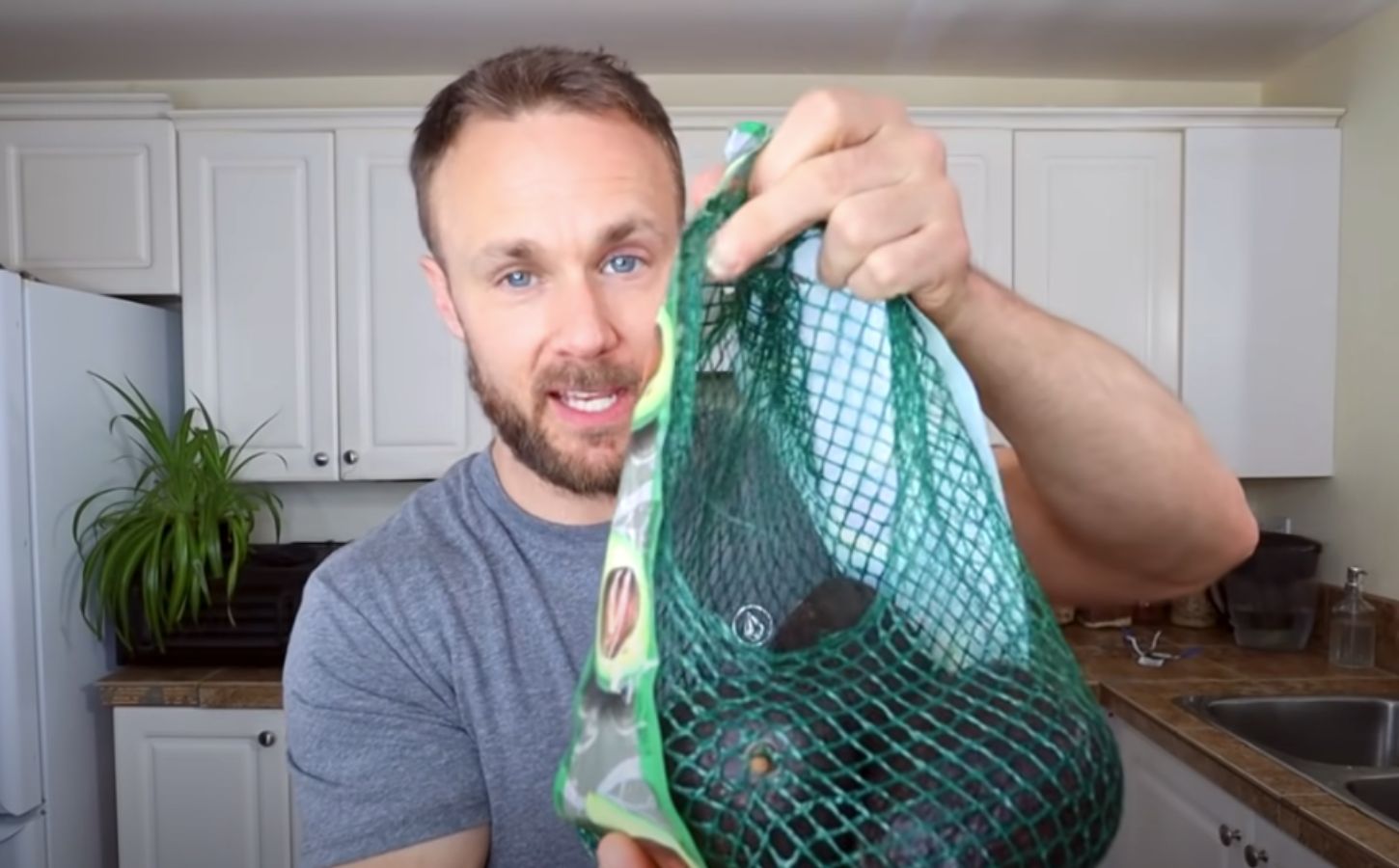 Plant-based nutritionist Derek Simnett holding up a pack of avocados for a video on vegan food hacks